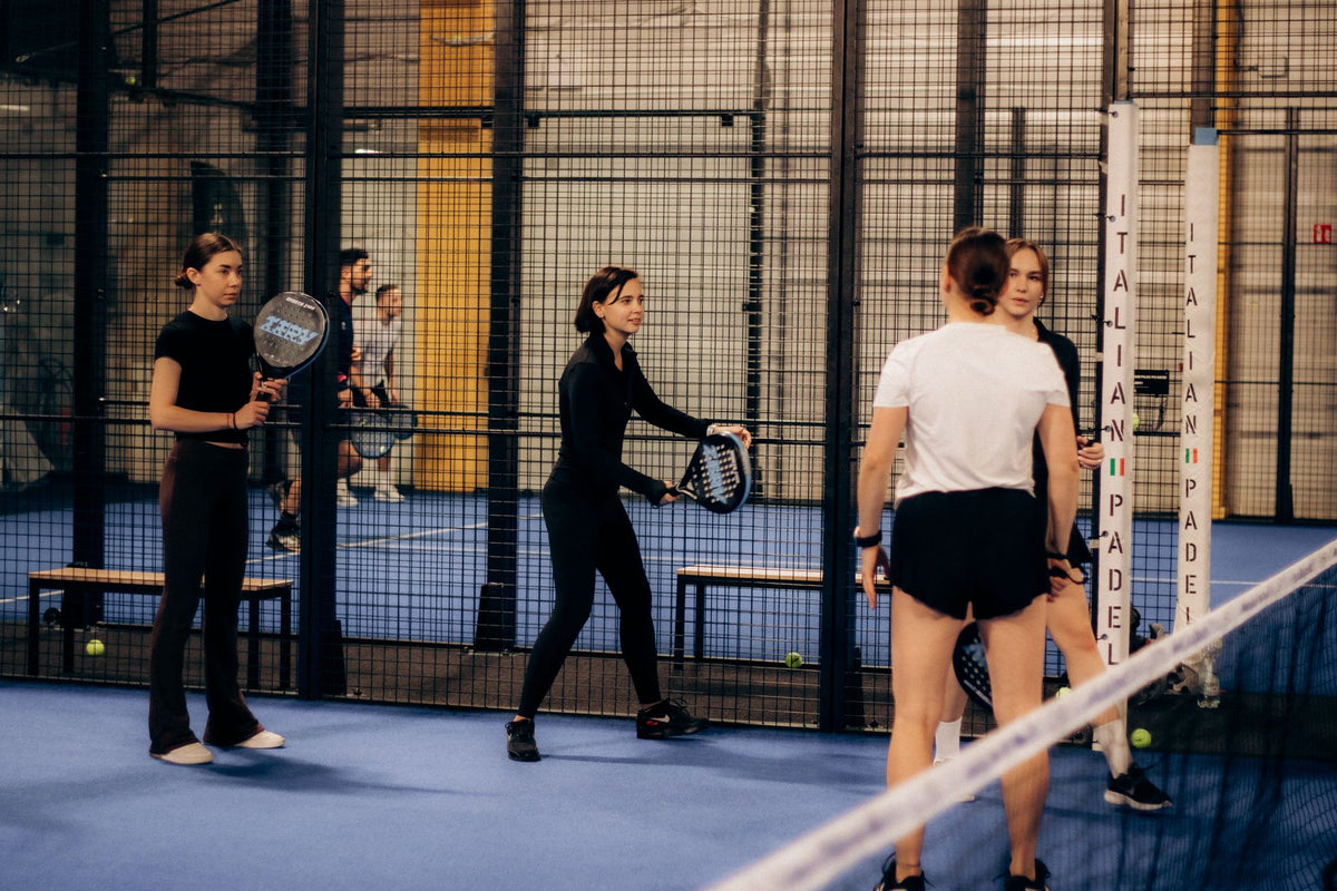 Giocatori di padel in campo indoor durante una partita di torneo